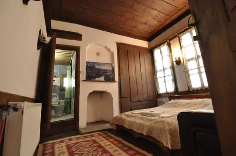 Ahşap tavanlı odada yatak ve pencereler